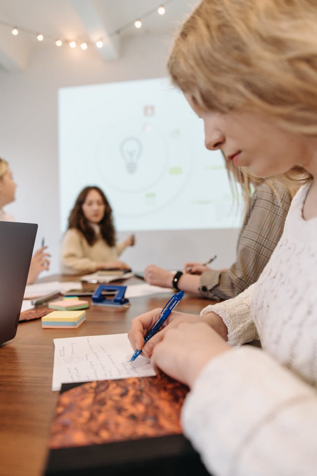 Persona durante una riunione di lavoro mentre prende appunti